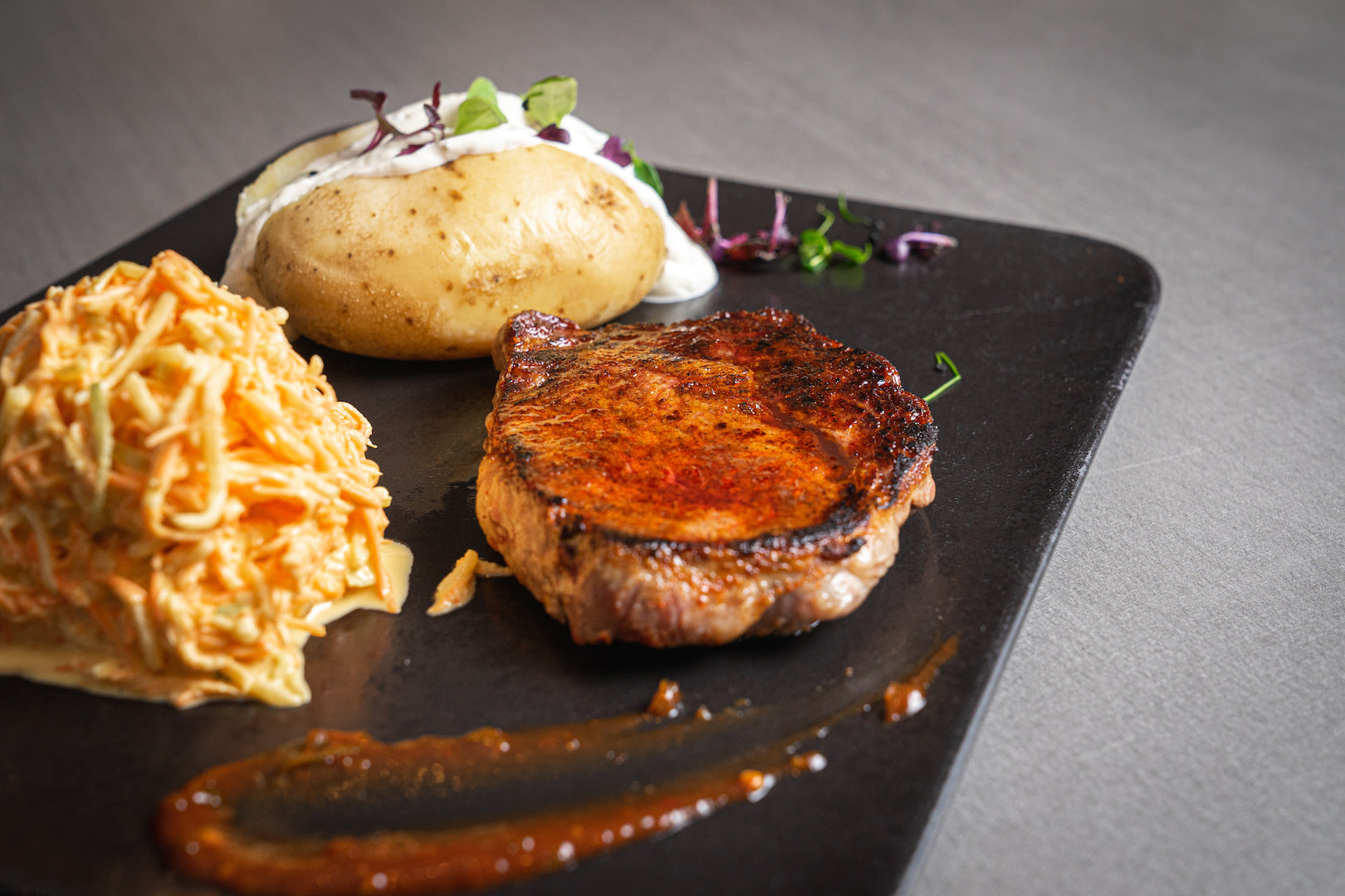 200g Argentisches Rib Eye Steak vom Black Angus Beef mit Ofenkartoffel, Sour-Cream und Farmersalat. Dazu 61er-Chipottle-BBQ-Sauce